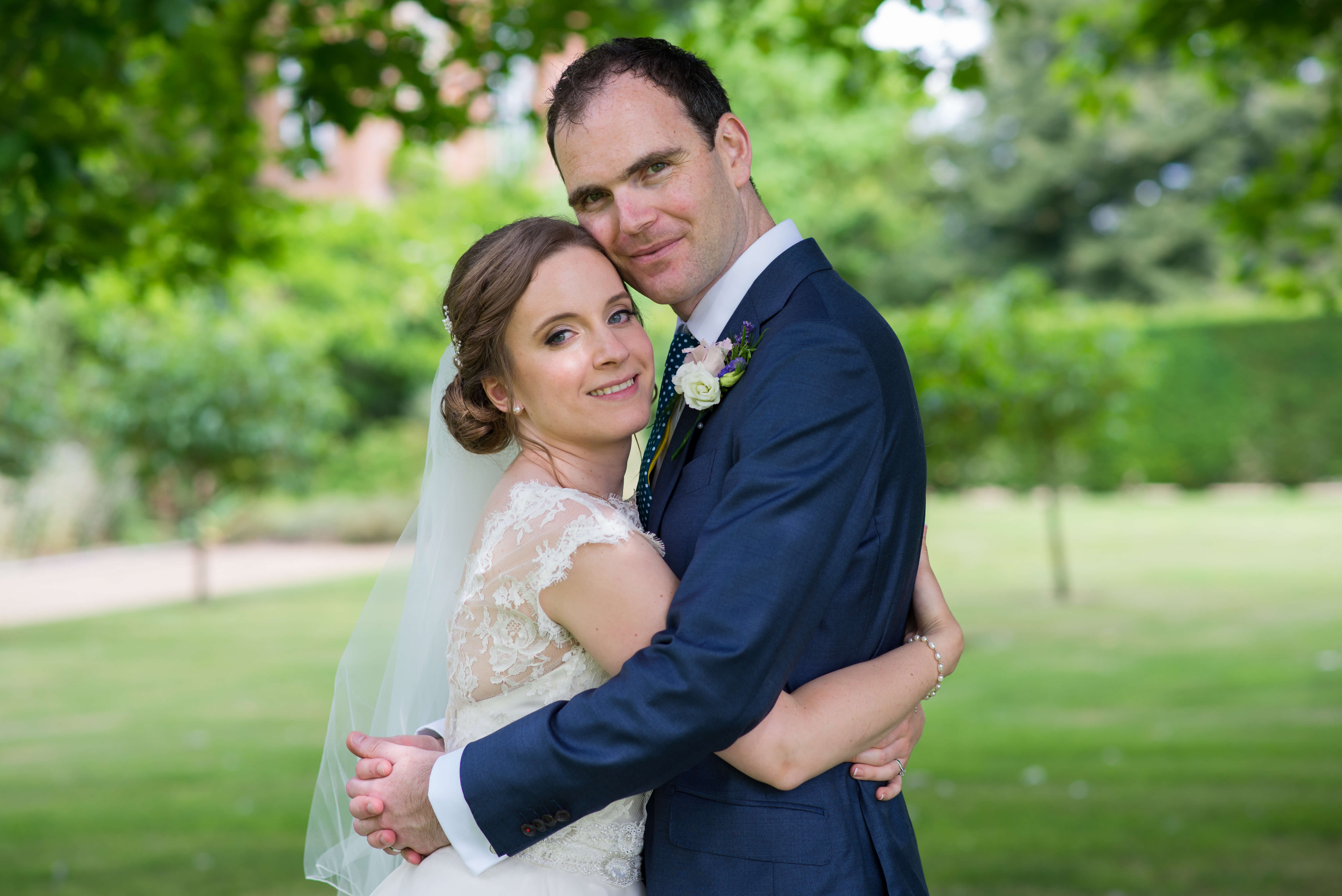 A bride and groom hugging in the gardens of Kingston Bagpuize in Oxfordshire